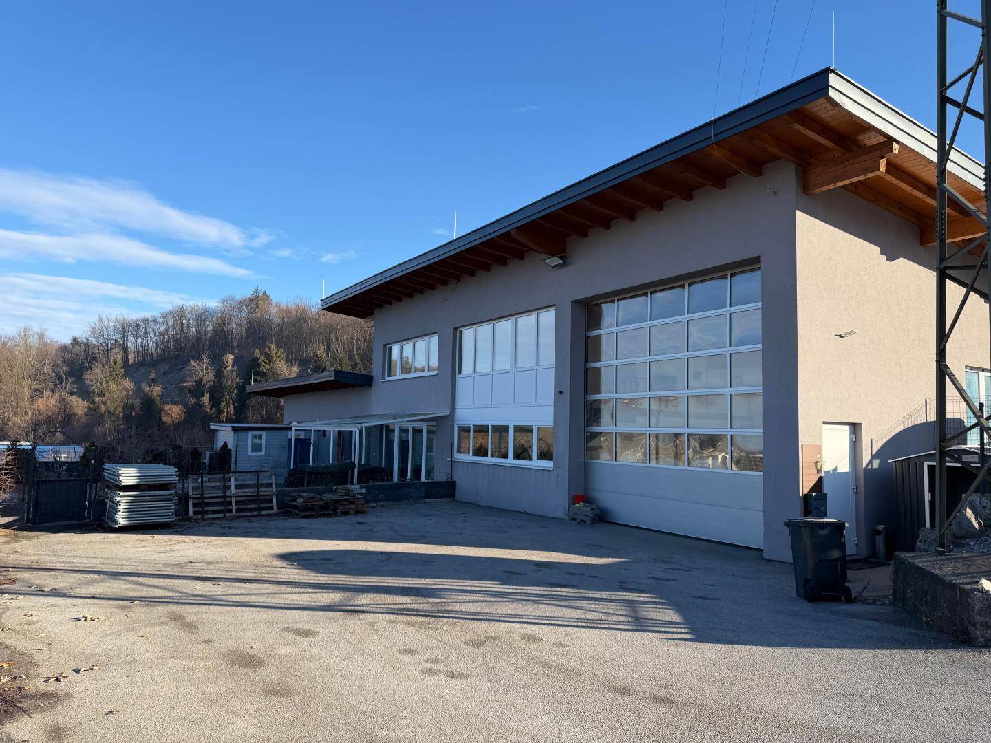 Modernes Geschäftsgebäude mit großen Garagentoren und Fenstern, umgeben von einer asphaltierten Fläche.