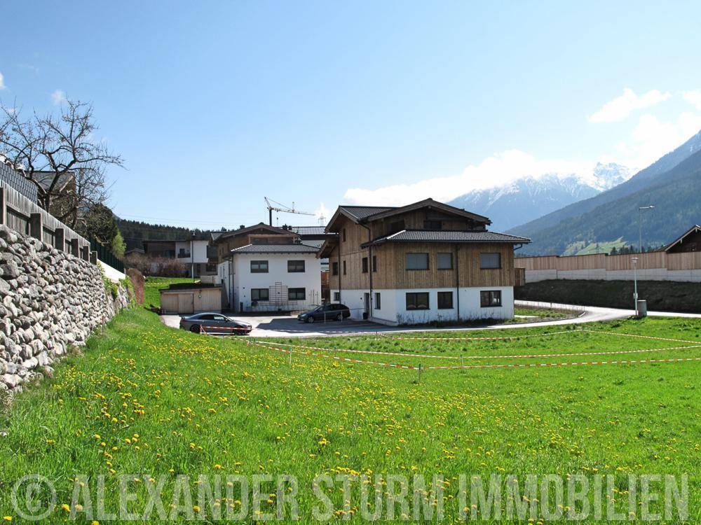 Zwei moderne Wohnhäuser in einer grünen Umgebung mit Blick auf die umliegenden Berge.