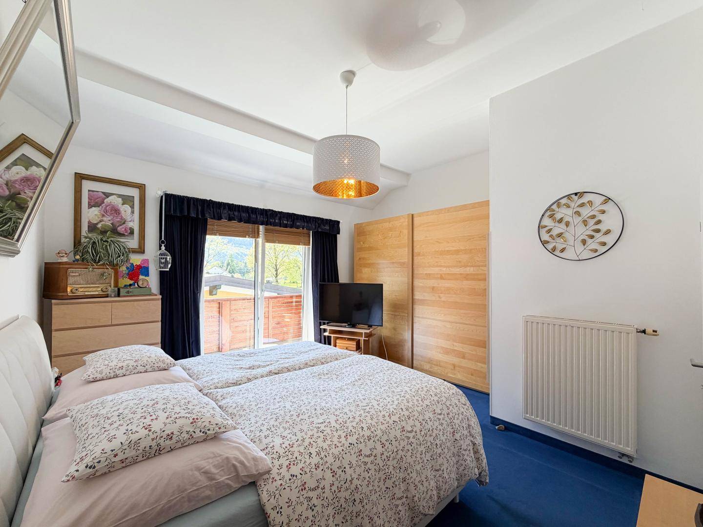 Gemütliches Schlafzimmer mit Doppelbett, Holzschränken und Zugang zu einem Balkon.