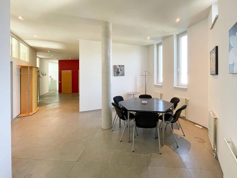 Heller, offener Bürobereich mit kleinem Besprechungstisch, Säule und Zugang zu weiteren Räumen.