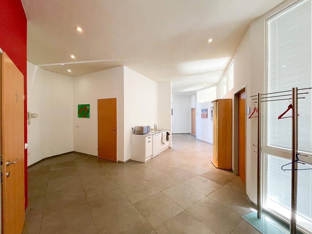 Offener Bürobereich mit kleiner Küchenzeile, Mikrowelle und Fliesenboden, ideal für Pausen.
