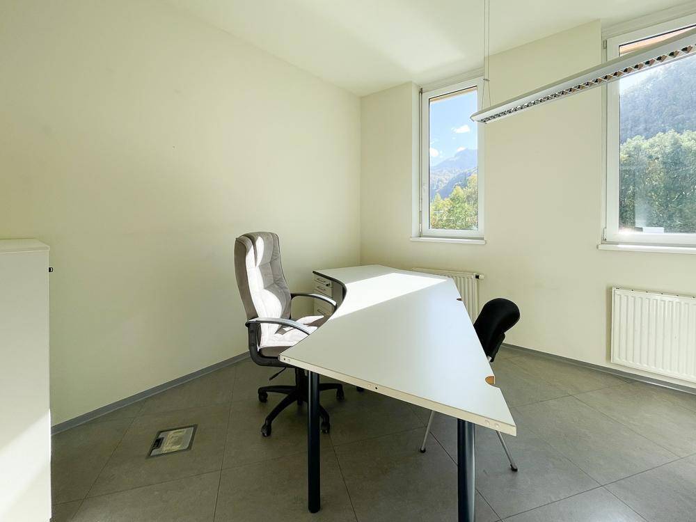 Kleines, helles Büro mit Schreibtisch, Bürostuhl und Fenstern, die einen schönen Bergblick bieten.