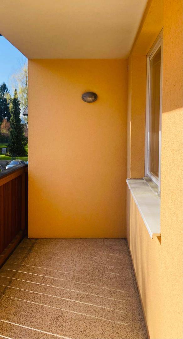 Leerer Balkon mit Fliesenboden und einer Wandleuchte, bereit zur individuellen Gestaltung.