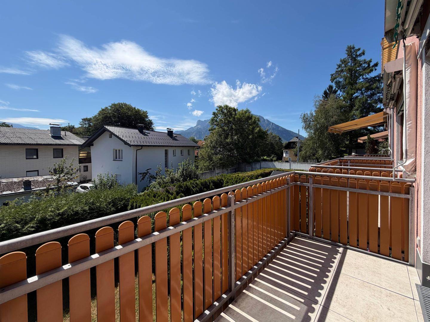 Sonniger Balkon mit Holzelementen und Blick auf die umliegende Berglandschaft.
