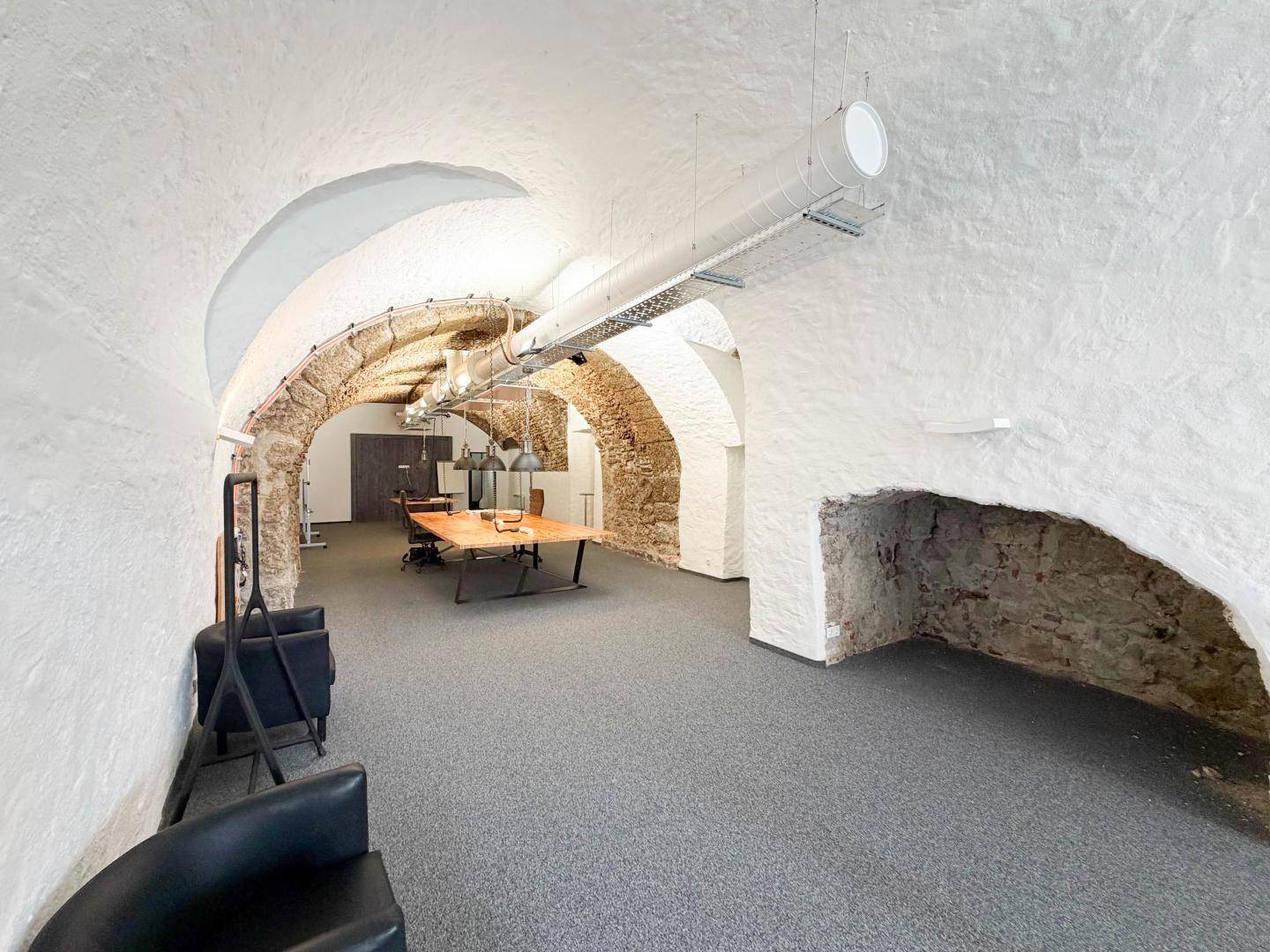 Blick in das weitläufige Büro mit weiß getünchten Wänden, freigelegten Steinbögen und bequemen Sitzgelegenheiten.