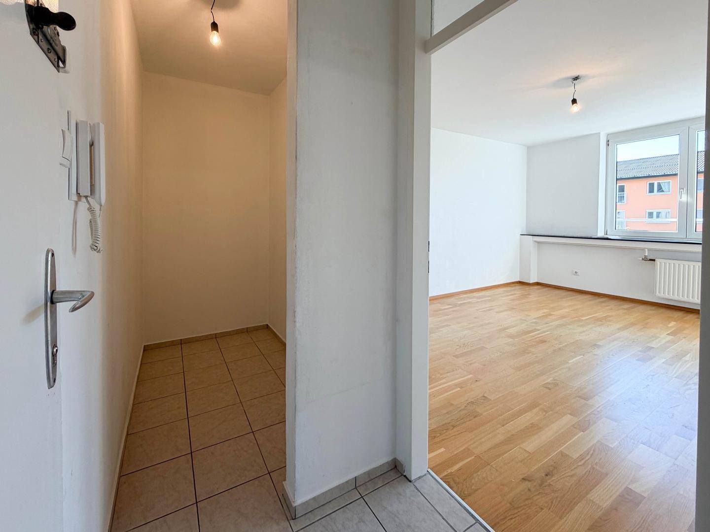 Eingangsbereich mit Fliesenboden und Blick in das angrenzende, helle Wohnzimmer.