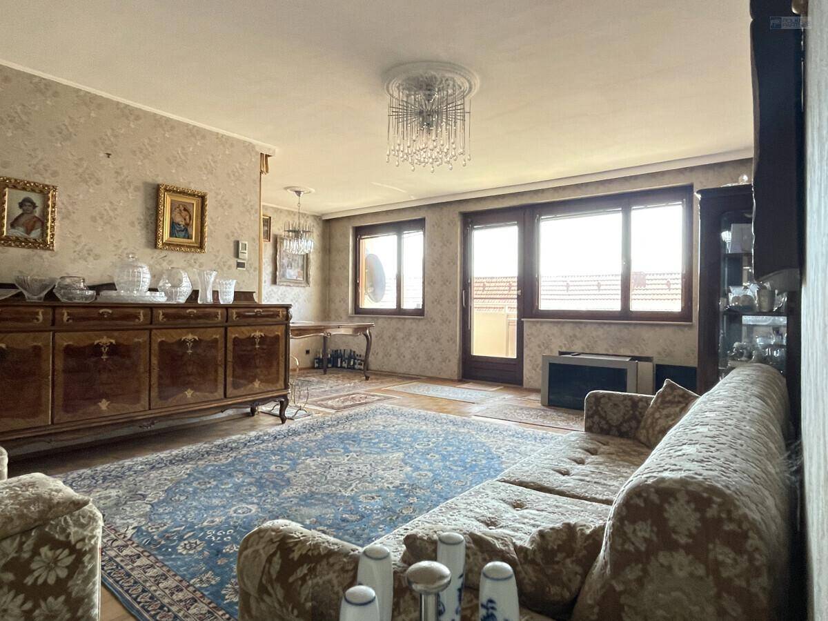 Geräumiges Wohnzimmer mit traditionellen Möbeln, Kronleuchter und Zugang zu einem Außenbereich.