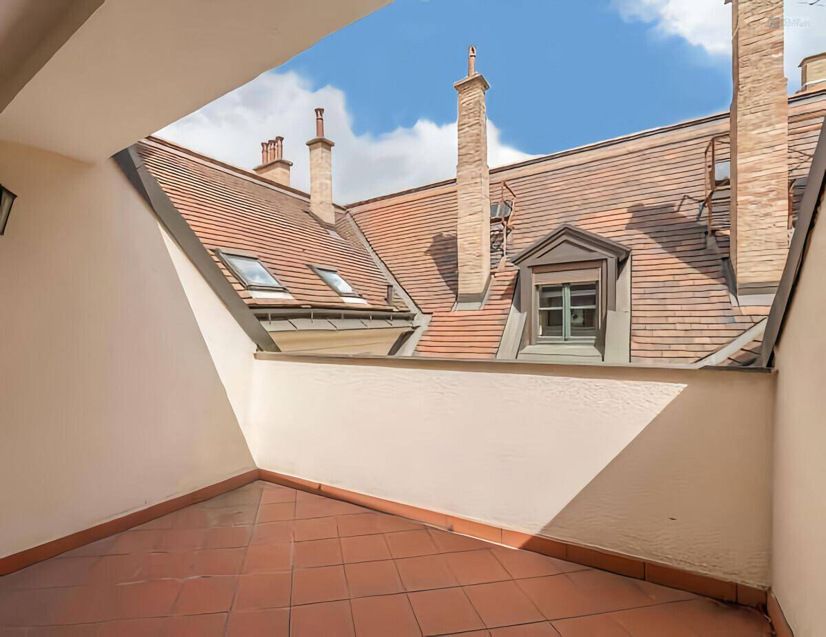 Eine geflieste Terrasse mit Blick auf die umliegenden Dächer und Schornsteine.