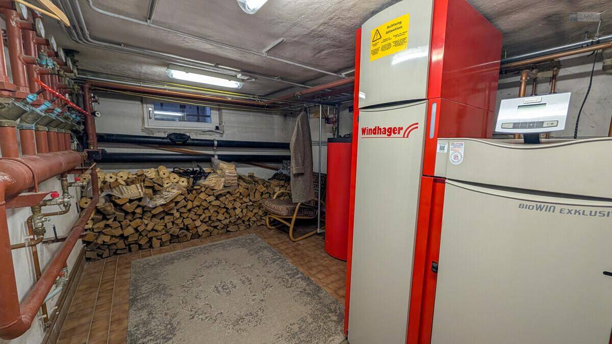 Heizungsraum mit modernen Biomasse-Heizkesseln und gelagertem Brennholz.