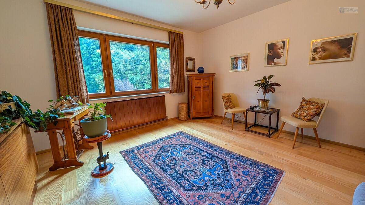 Geräumiges Schlafzimmer mit Holzboden, großem Fenster und traditionellem Teppich.