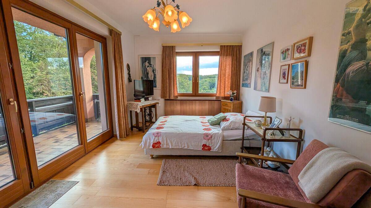 Gemütliches Schlafzimmer mit Holzboden, Balkonzugang und malerischem Ausblick.