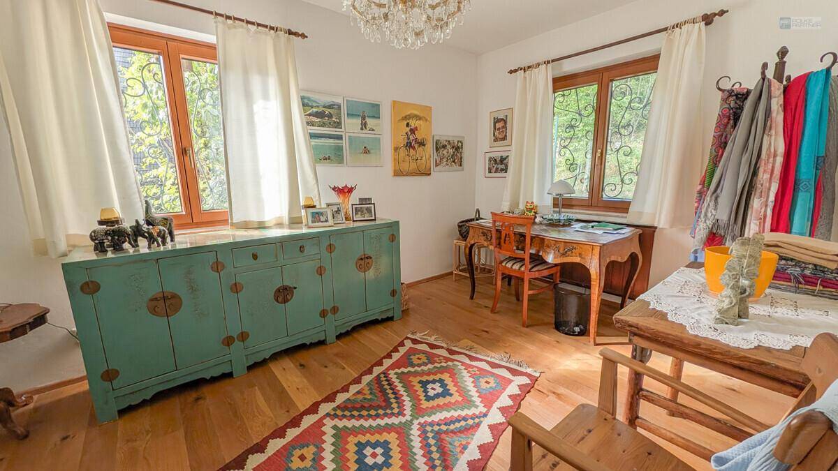 Heller Arbeitsbereich mit Holzboden, großem Fenster und einem antiken Sideboard.