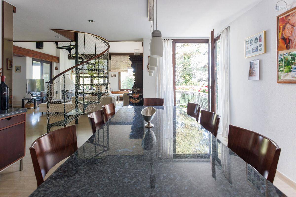 Eleganter Essbereich mit großem dunklem Tisch, Holzstühlen und Zugang zu einem Balkon.
