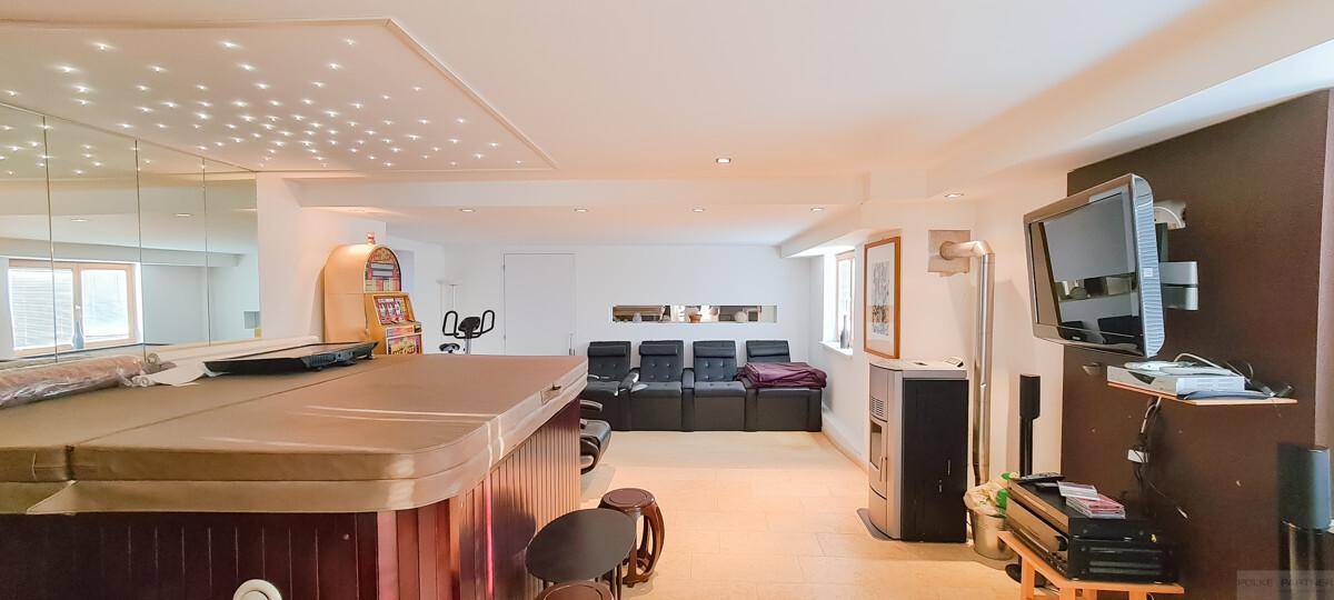 Großer Wellnessbereich mit Whirlpool, Spiegelwand und Unterhaltungselektronik.