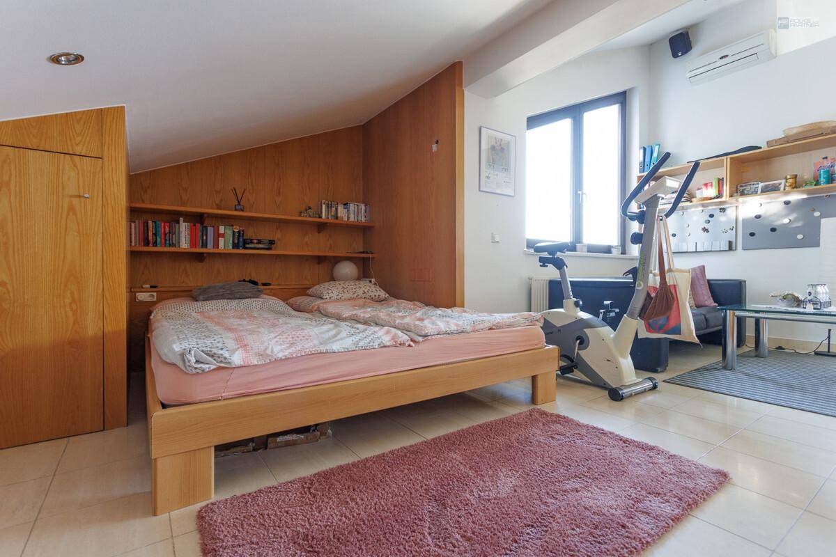 Geräumiges Schlafzimmer im Dachgeschoss mit zwei Betten, Fitnessgerät und Schrägen.