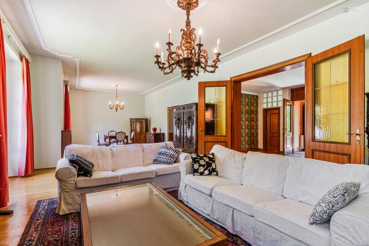 Elegantes Wohnzimmer mit zwei weißen Sofas, Holzboden und Kronleuchter.