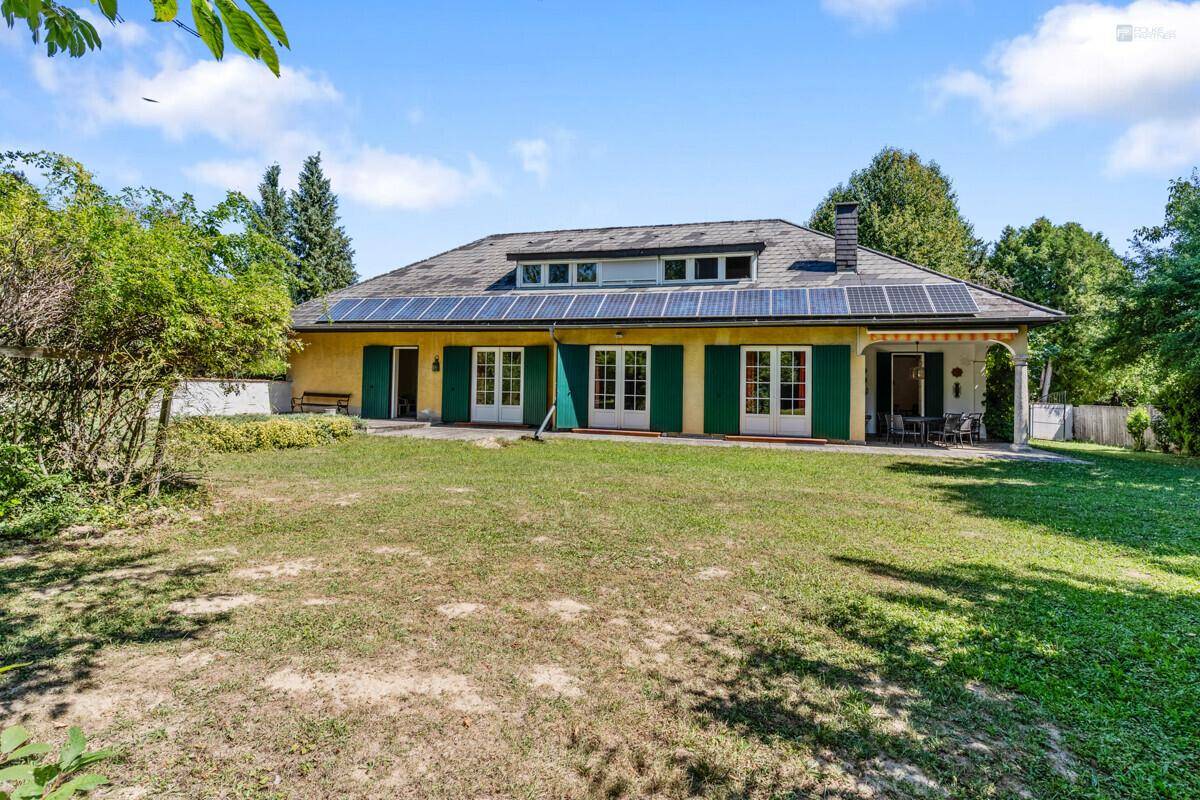 Großer, sonniger Garten hinter dem Haus mit Rasenfläche und Solaranlage auf dem Dach.