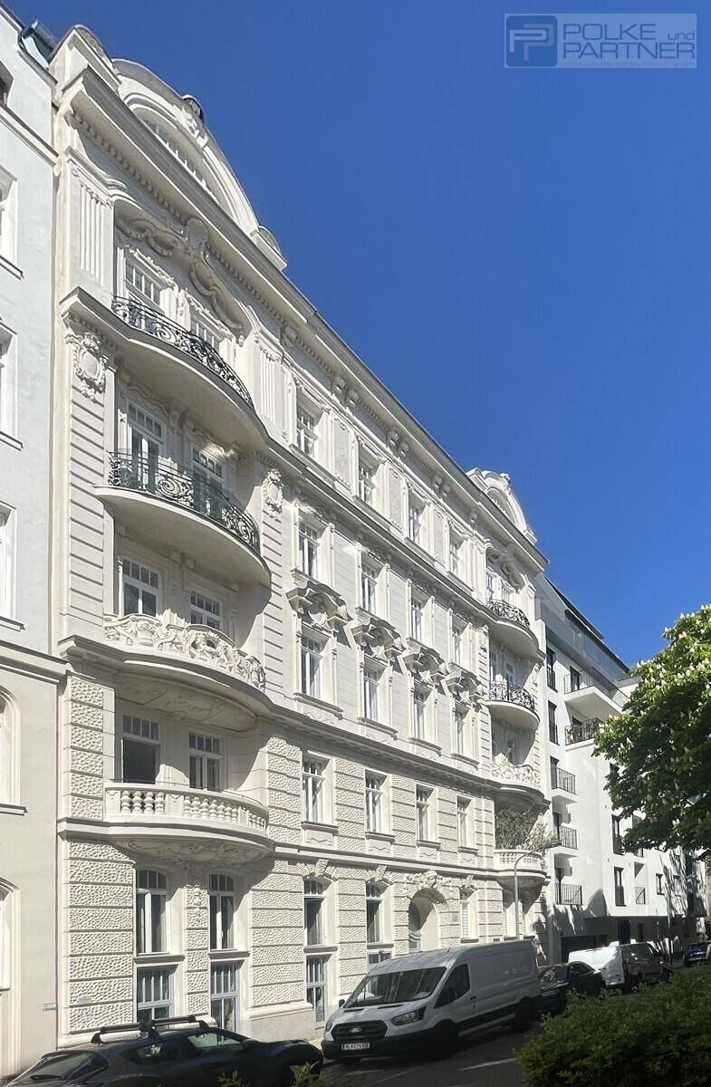 Eindrucksvolle historische Fassade eines Altbaus mit reich verzierten Balkonen unter blauem Himmel.
