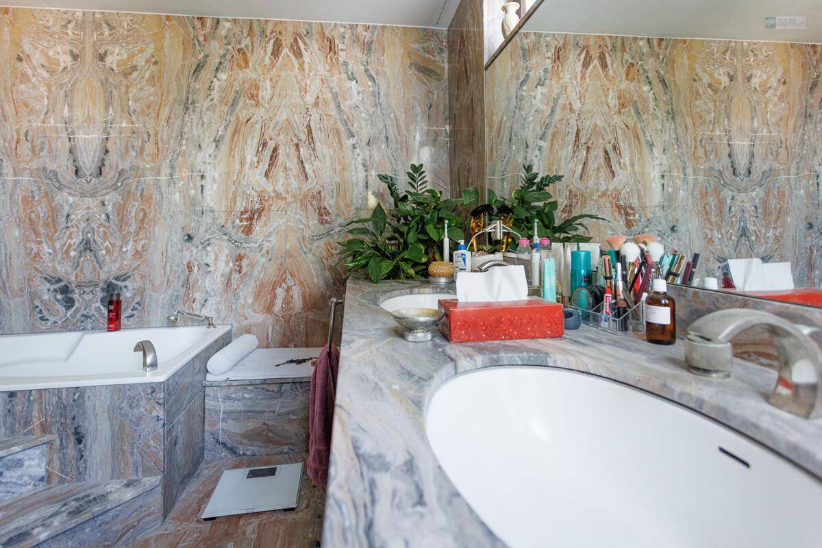 Luxuriöses Badezimmer mit doppelten Waschbecken, Badewanne und auffälligen Marmorwänden.