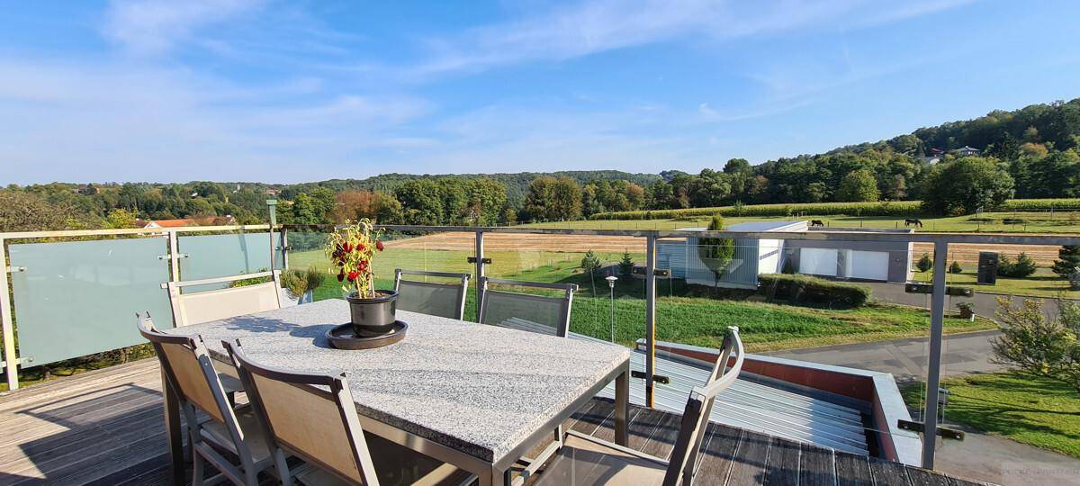 Sonniger Essbereich auf der Terrasse mit weitem Blick über die grüne Landschaft.