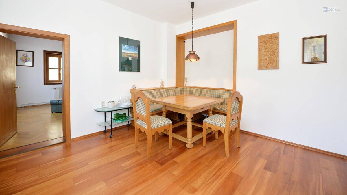 Heller Essbereich mit Holztisch, Eckbank und Stühlen auf glänzendem Holzfußboden.