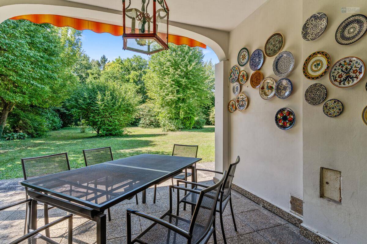 Überdachte Terrasse mit Esstisch, Stühlen und Blick auf den grünen Garten.