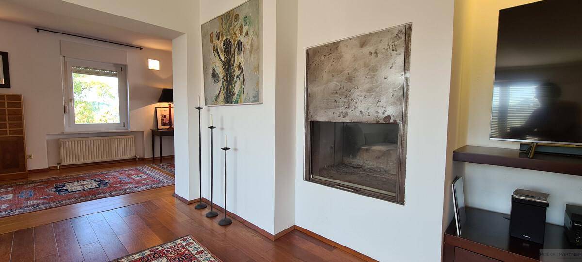 Heller Wohnbereich mit Holzboden, Kamin und Kunstwerken an den Wänden.