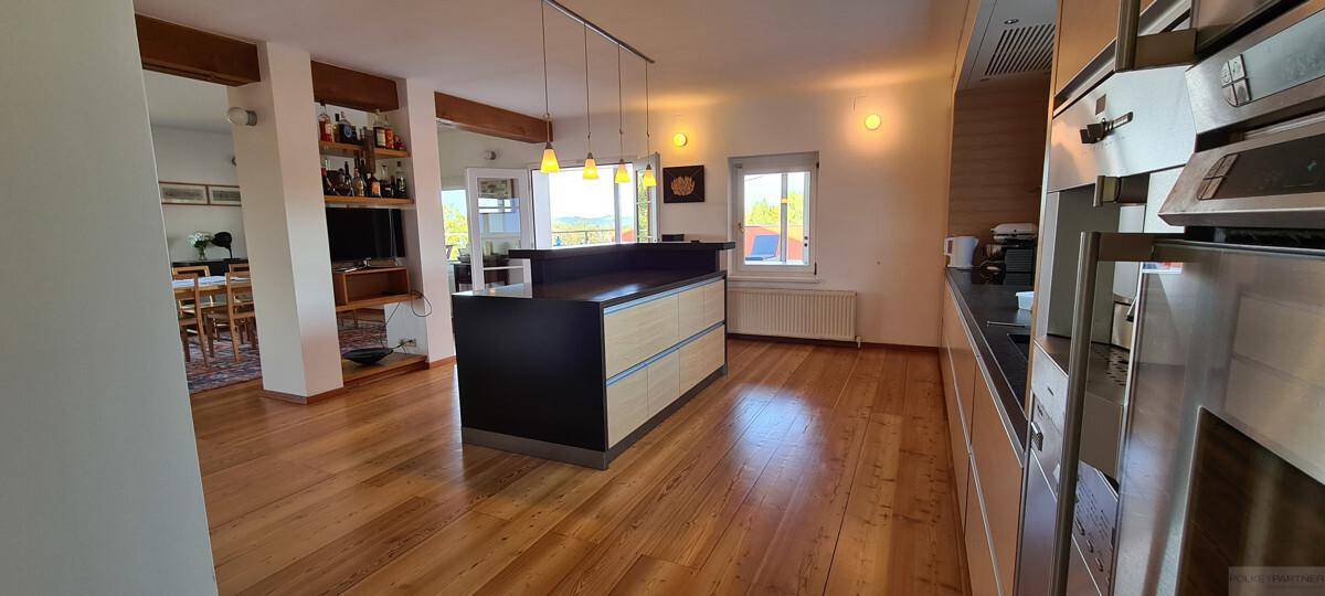 Moderne Küche mit Holzboden, Kochinsel und hochwertigen Einbaugeräten.