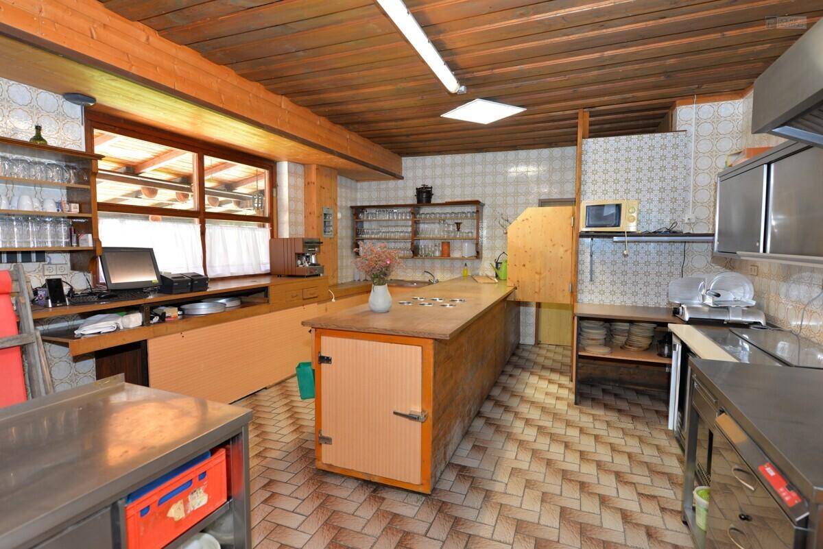 Geräumige Küche mit Holzbalkendecke, gefliestem Boden und professionellen Edelstahlarbeitsflächen.