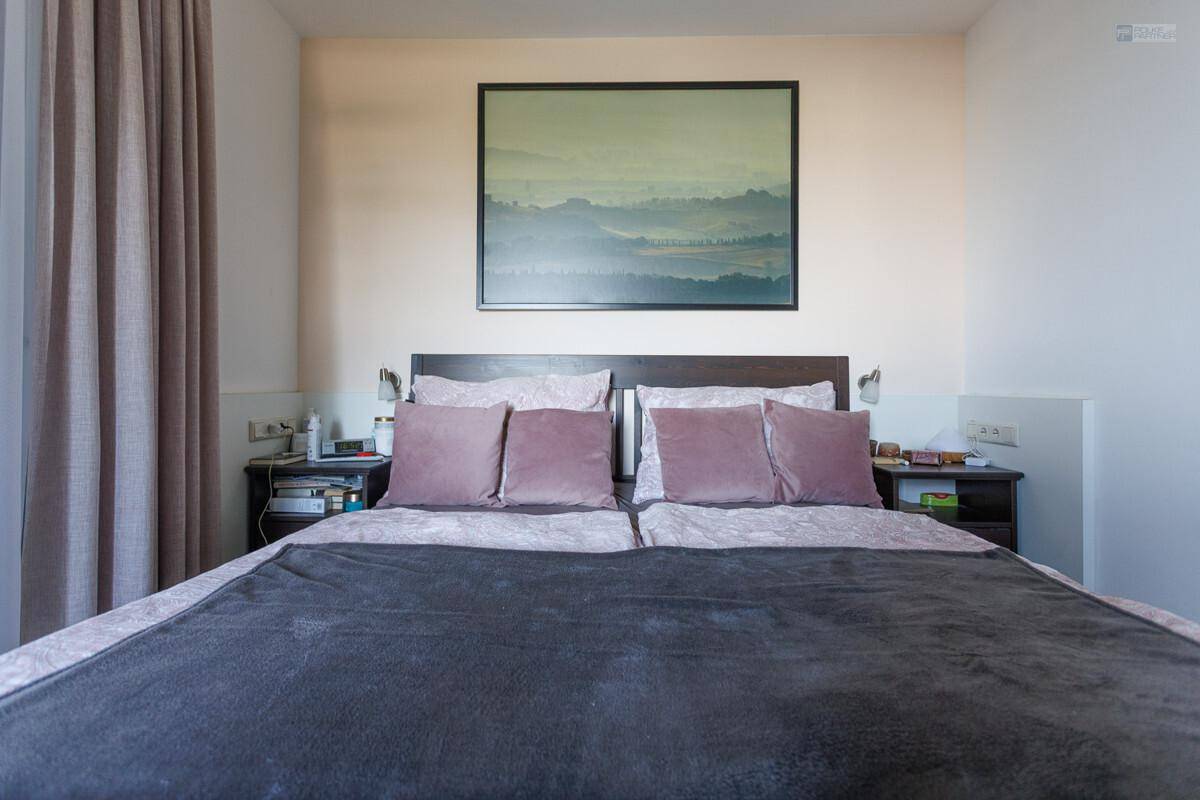 Gemütliches Schlafzimmer mit Doppelbett, Nachttischen und einem Bild über dem Bett.