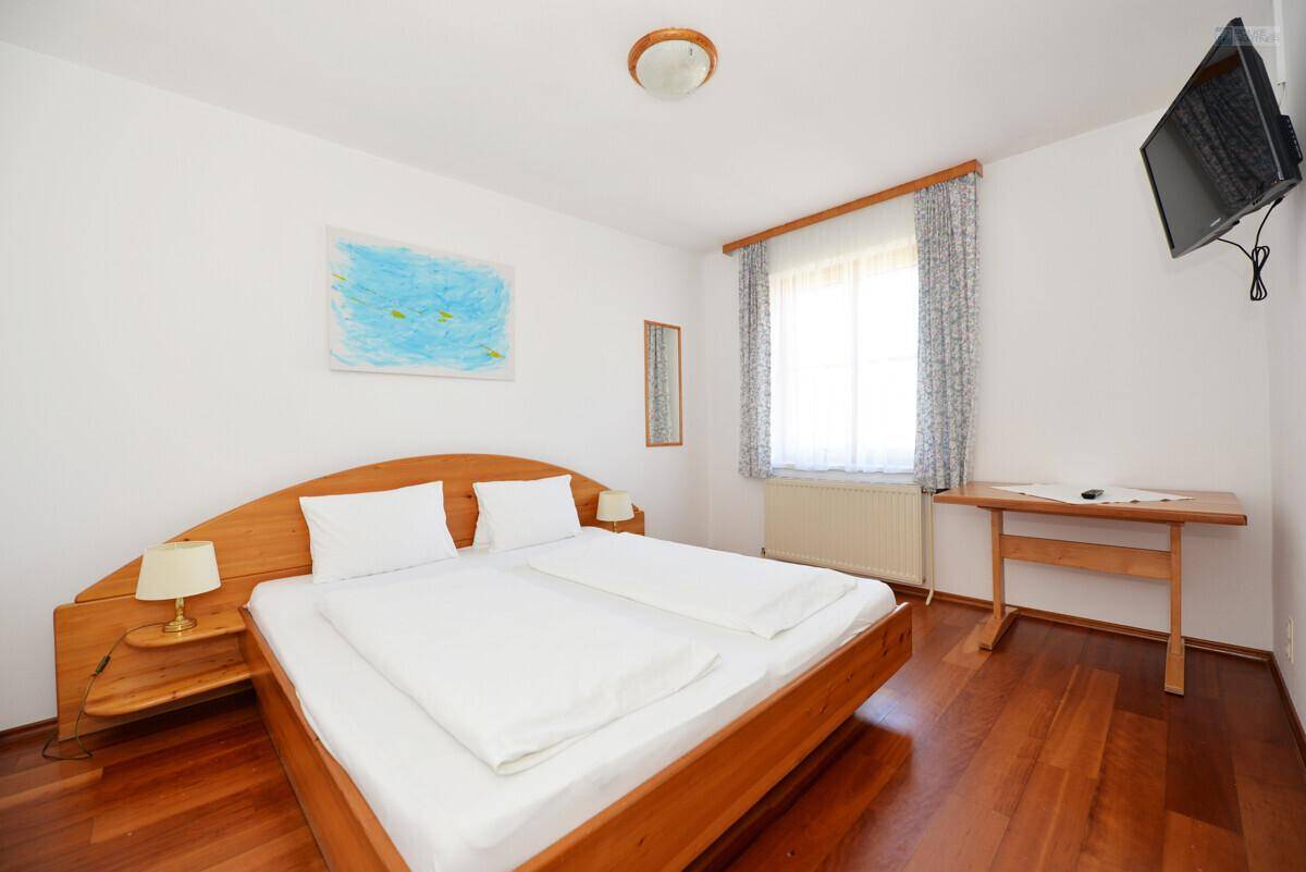 Helles Schlafzimmer mit Doppelbett aus hellem Holz, Holzfußboden und einfacher, freundlicher Dekoration.
