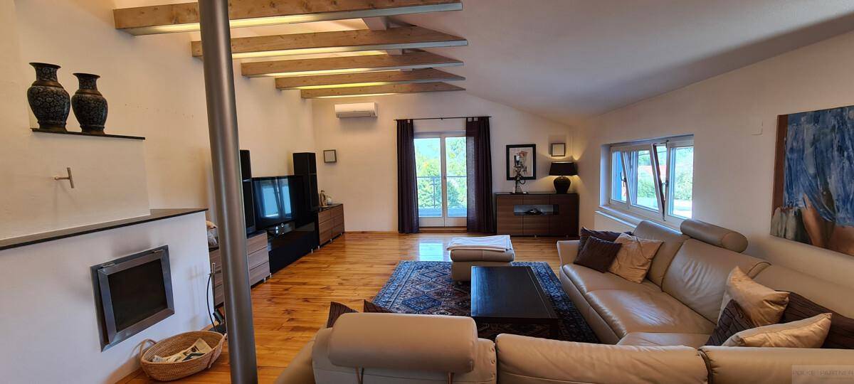 Gemütliches Wohnzimmer mit Holzboden, bequemer Couch und sichtbaren Deckenbalken.