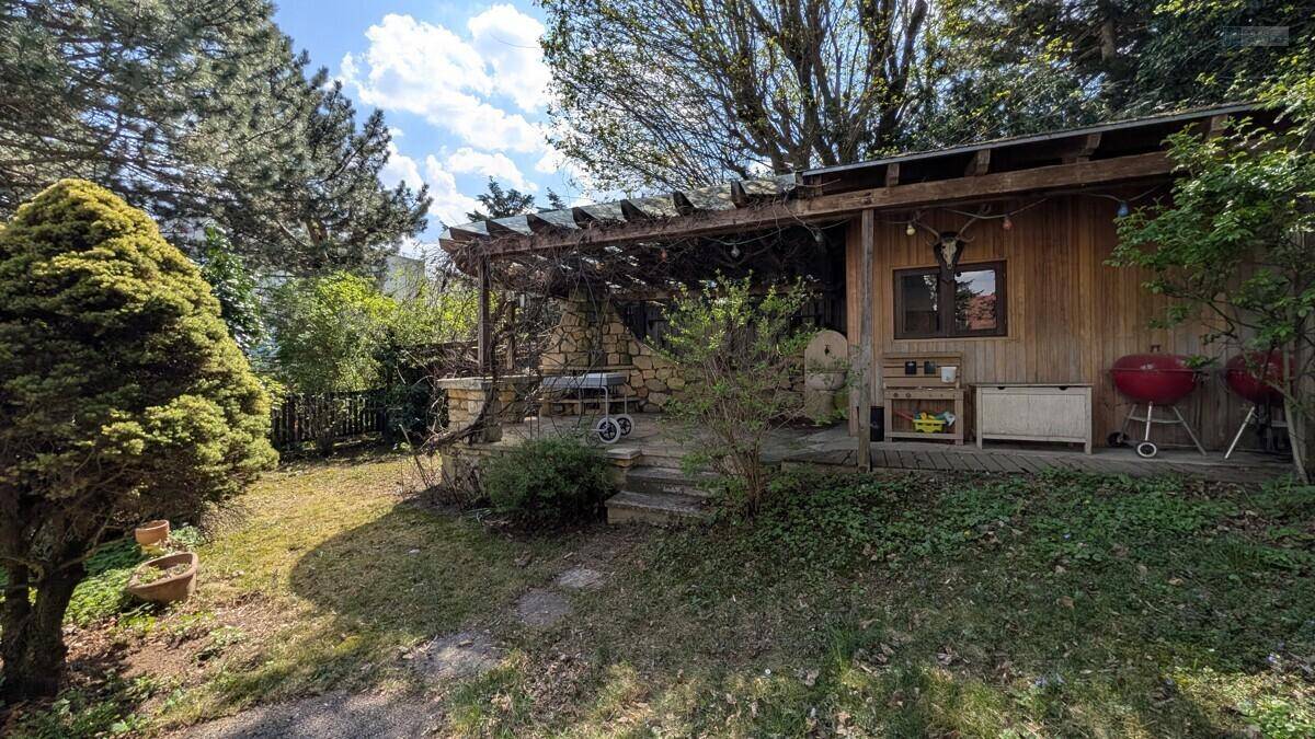 Gemütlicher Grillbereich im Garten mit Holzpergola und Gartenhaus.