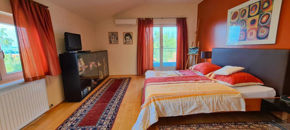 Gemütliches Schlafzimmer mit Holzboden, Doppelbett und Zugang zu einem Balkon.