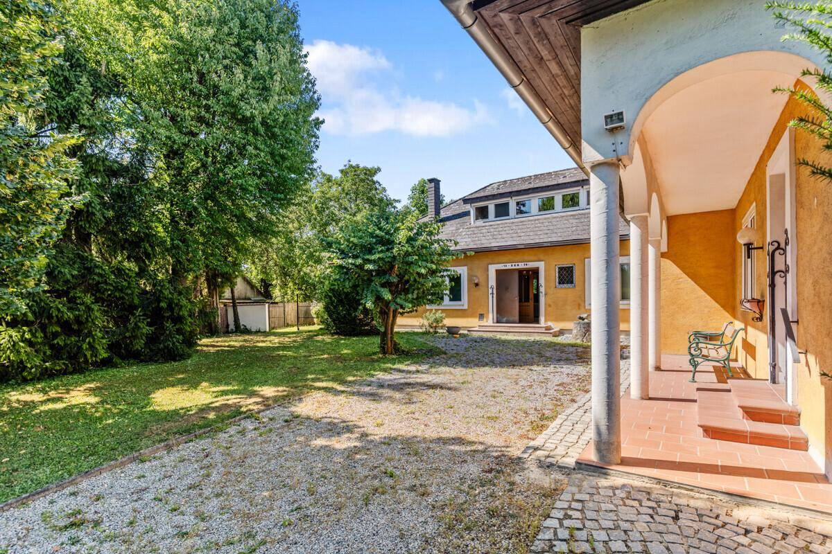 Rückansicht des Hauses mit großem Garten, Kiesweg und Säulenveranda.