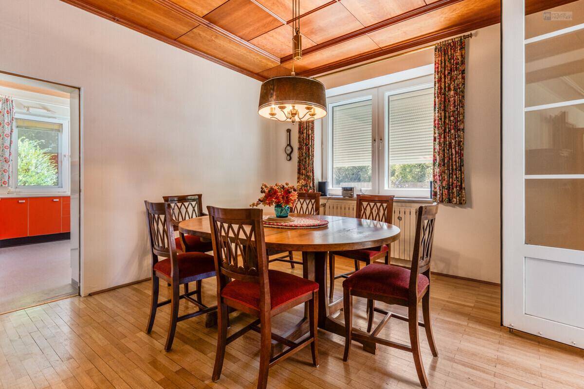 Gemütliches Esszimmer mit Holztisch, passenden Stühlen und Holzdecke.