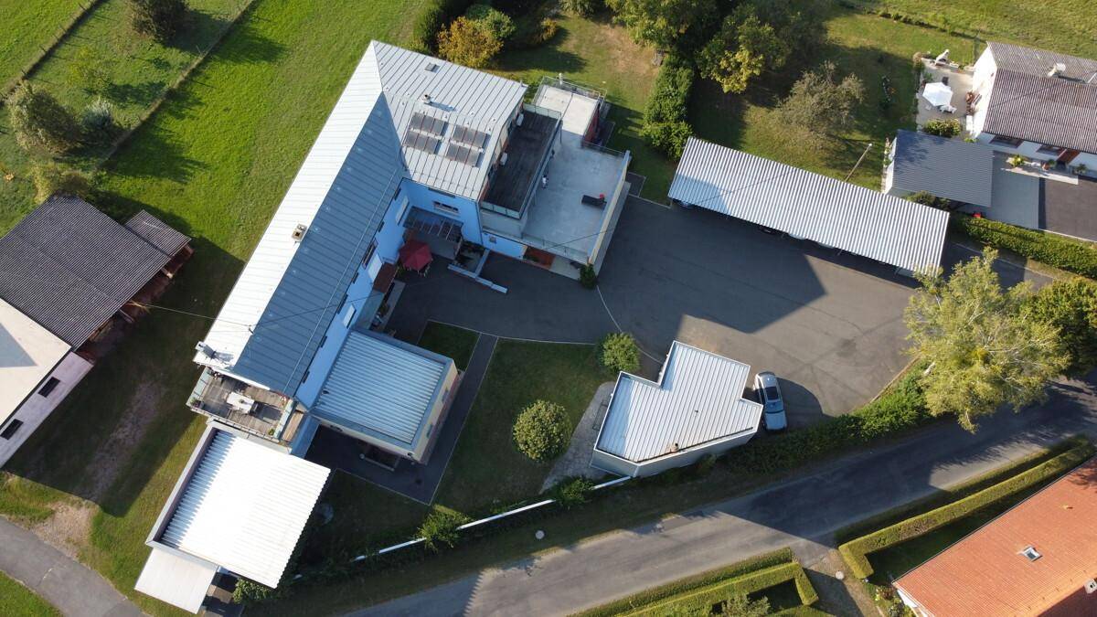 Luftaufnahme des Anwesens mit mehreren Gebäuden, Carports und Grünflächen.