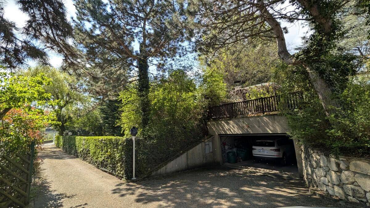 Zufahrt zur Tiefgarage mit üppiger Bepflanzung und Hecke entlang des Weges.