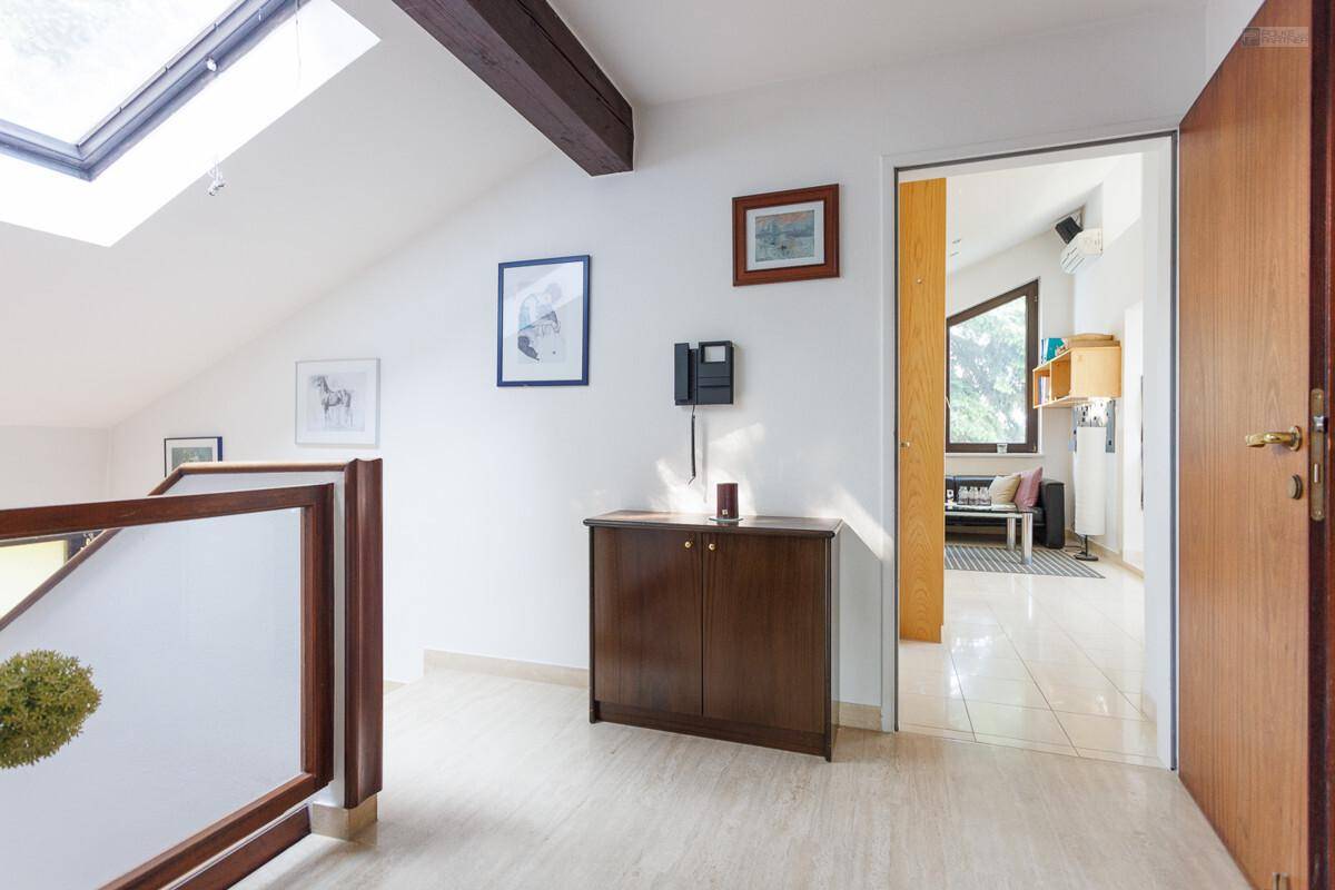 Heller Flur im Obergeschoss mit Dachfenster, Holzgeländer und Blick in den Wohnbereich.