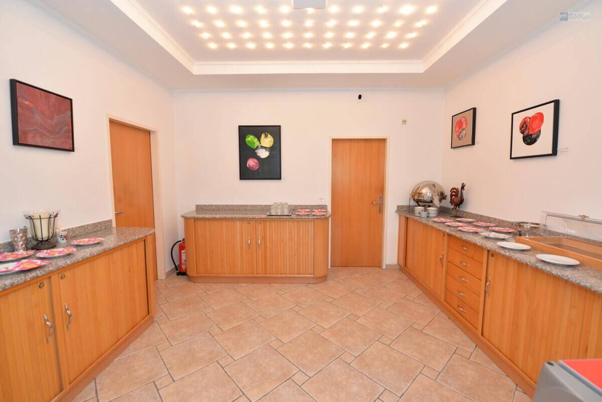 Heller Buffetbereich mit Holzschränken, Granitarbeitsplatten und Fliesenboden, bereit für Speisen.
