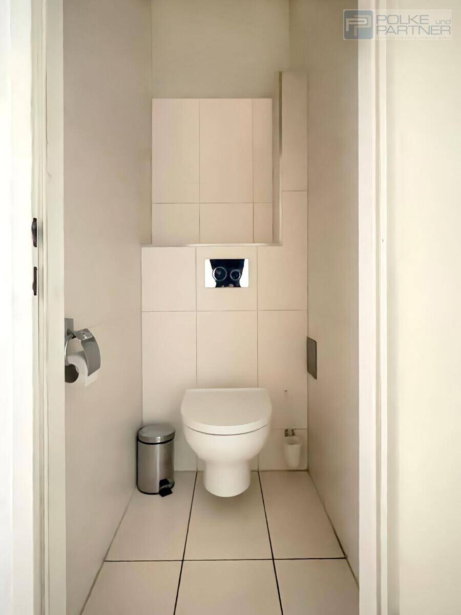 Separates WC mit wandhängender Toilette und modernen weißen Fliesen, sauber und funktional.