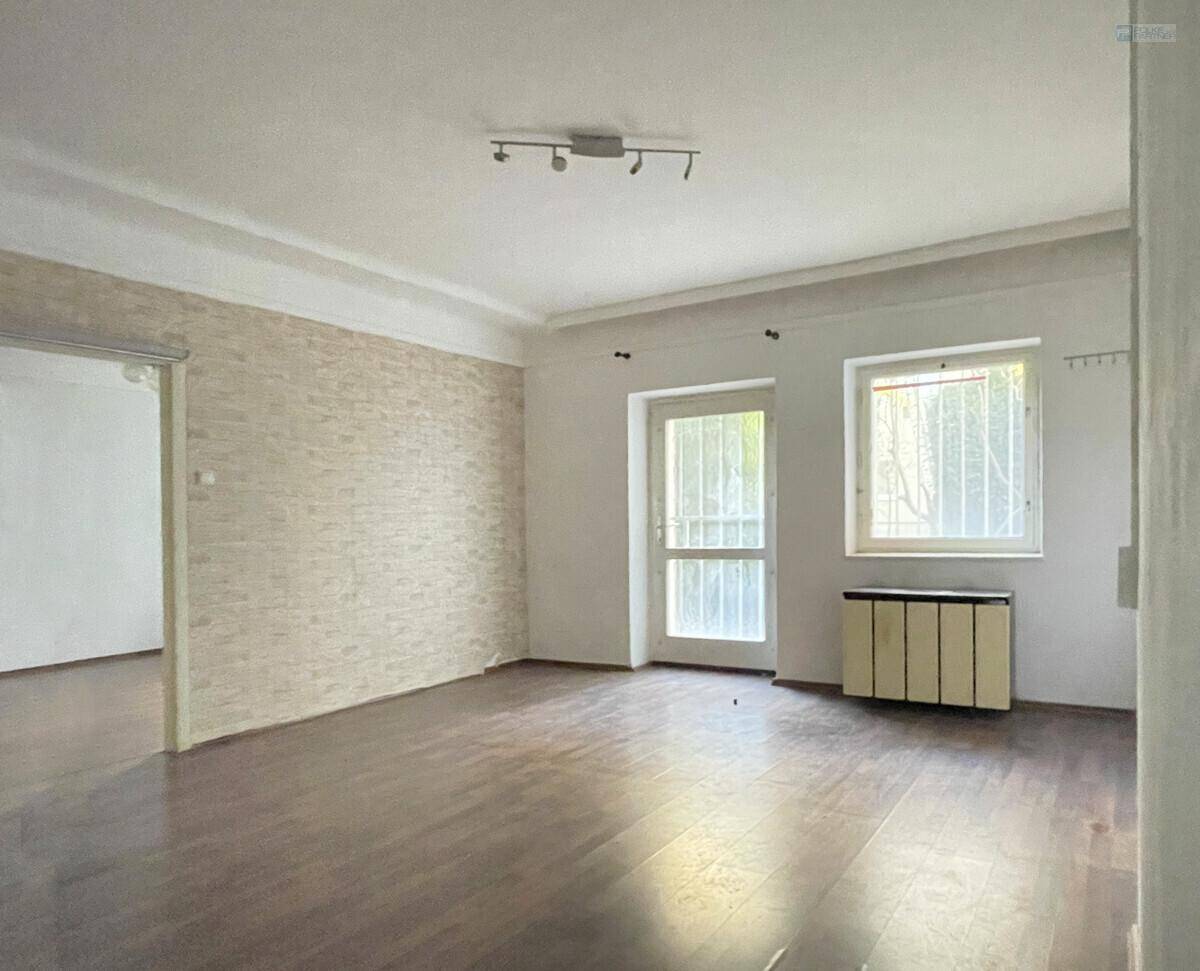Geräumiges Wohnzimmer mit Laminatboden, strukturierten Tapeten und Zugang zu einem Außenbereich.