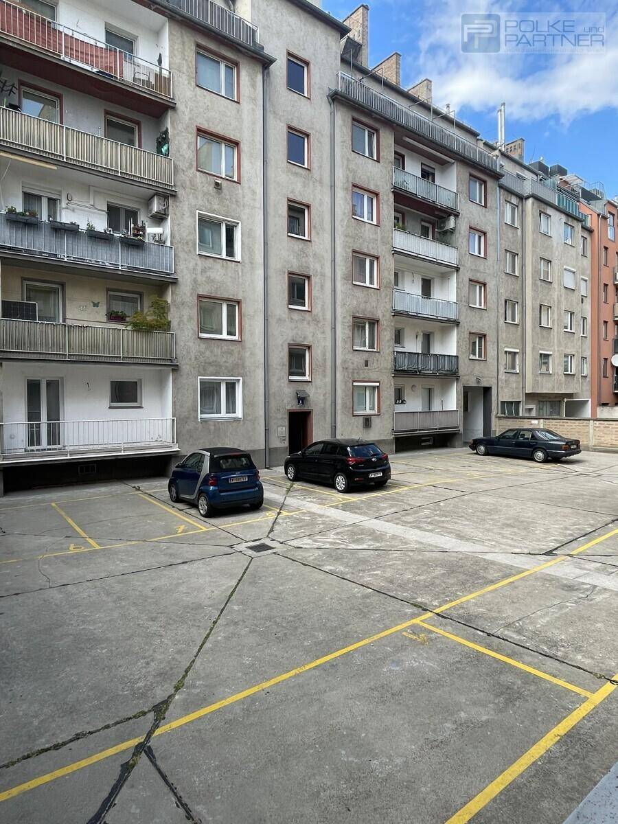 Ansicht der Gebäudefassade mit mehreren Balkonen und einem großen Außenparkplatz für Bewohner.