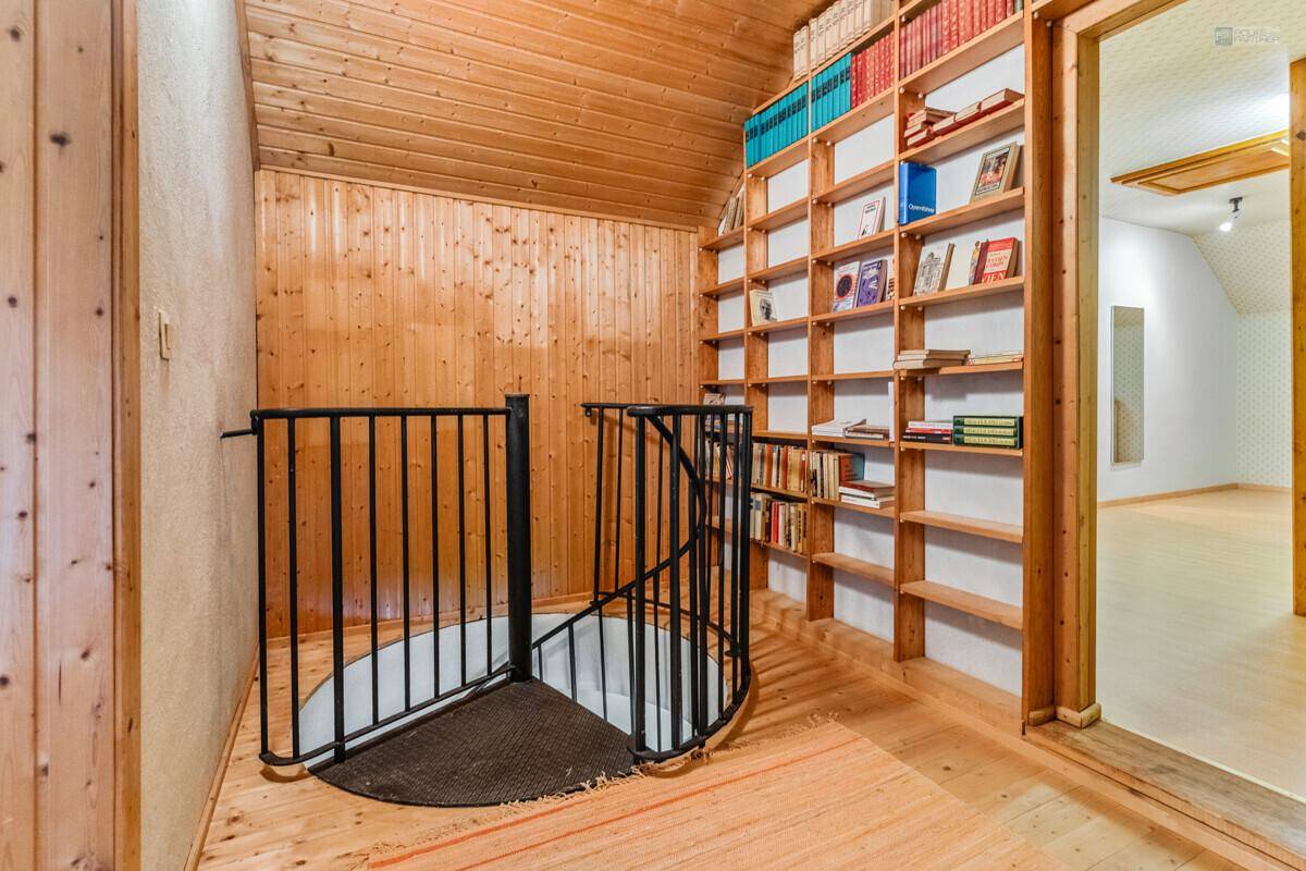 Gemütlicher Bereich mit Wendeltreppe, Holzvertäfelung und eingebauten Bücherregalen.