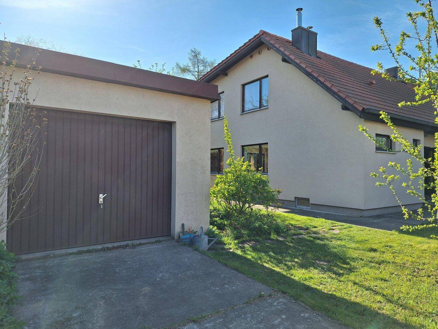 Seitenansicht des Hauses mit angrenzender Garage und gepflegtem Vorgartenbereich.