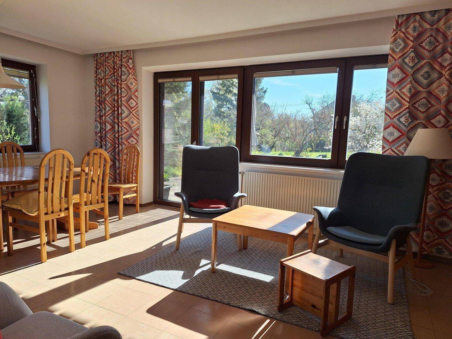Heller Wohn- und Essbereich mit großen Fenstern und direktem Blick in den Garten.