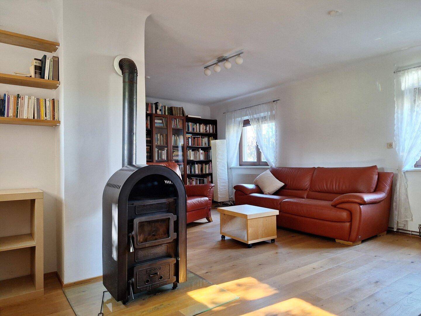 Gemütliches Wohnzimmer mit Holzboden, Kaminofen und Bücherregalen für entspannte Stunden.