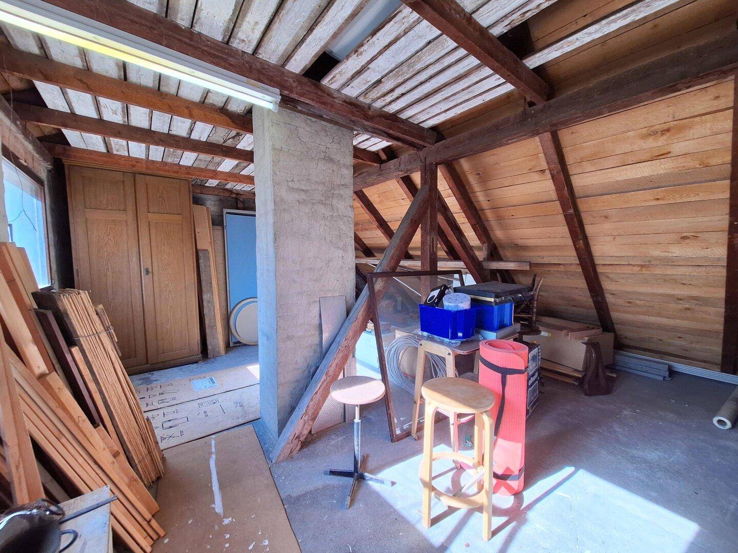 Unausgebauter Dachboden mit sichtbaren Holzbalken und Lagerfläche, bietet Ausbaupotenzial.