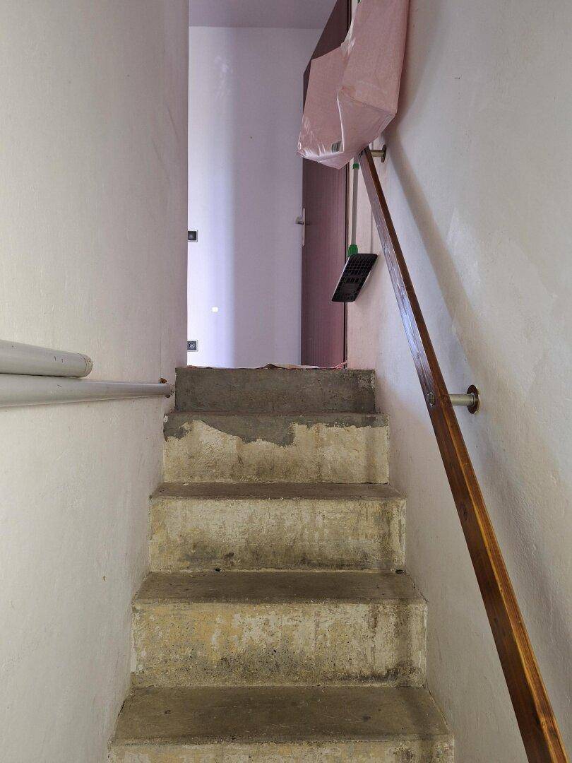 Unfertige Betontreppe mit Holzgeländer, die in ein oberes Stockwerk führt.