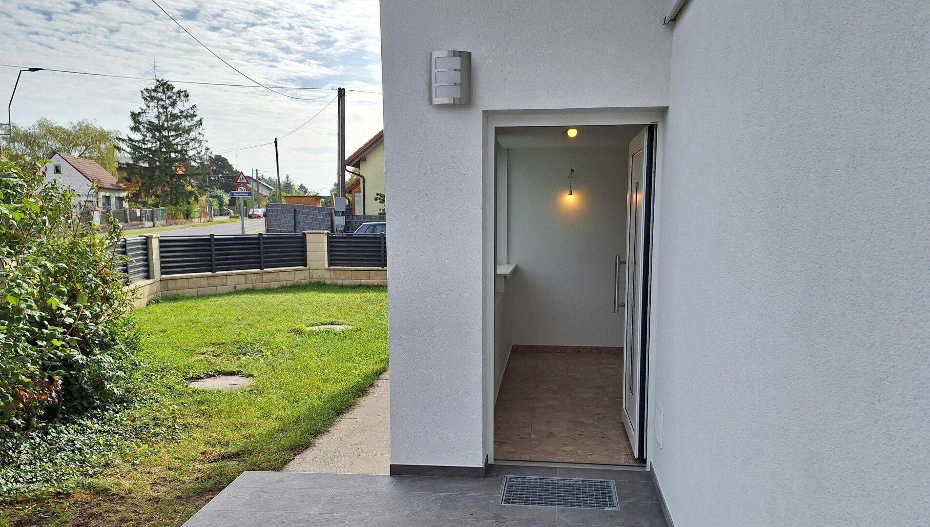 Eingangsbereich des Hauses mit moderner Haustür, Fliesenboden und Blick auf die Straße.